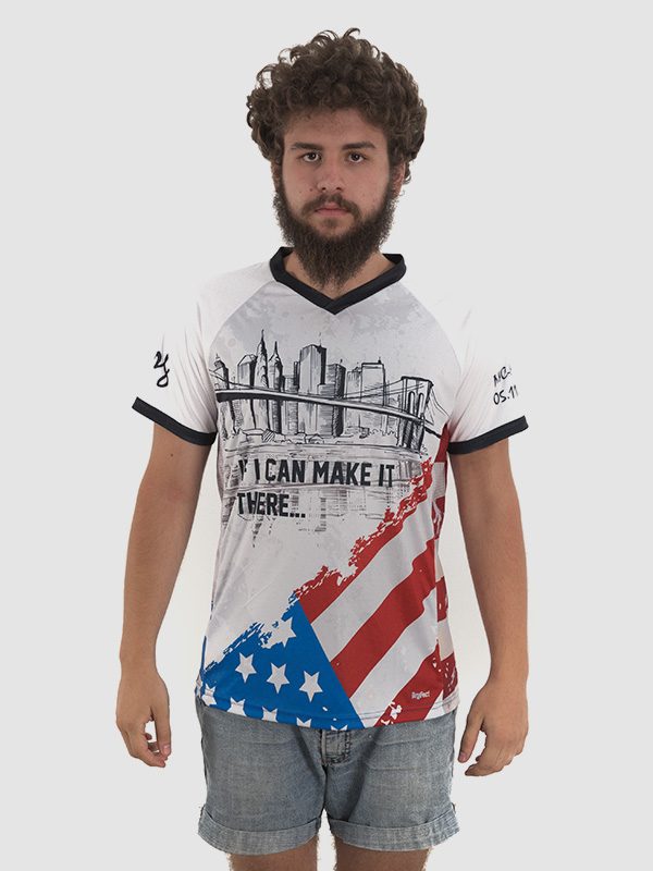 A male model wearing a white t-shirt with the American flag motive printed on the bottom half of the garment. Front side is shown.